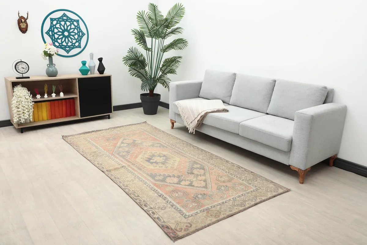 Vintage Anatolian rug in a living room setting with a gray sofa and wooden cabinet