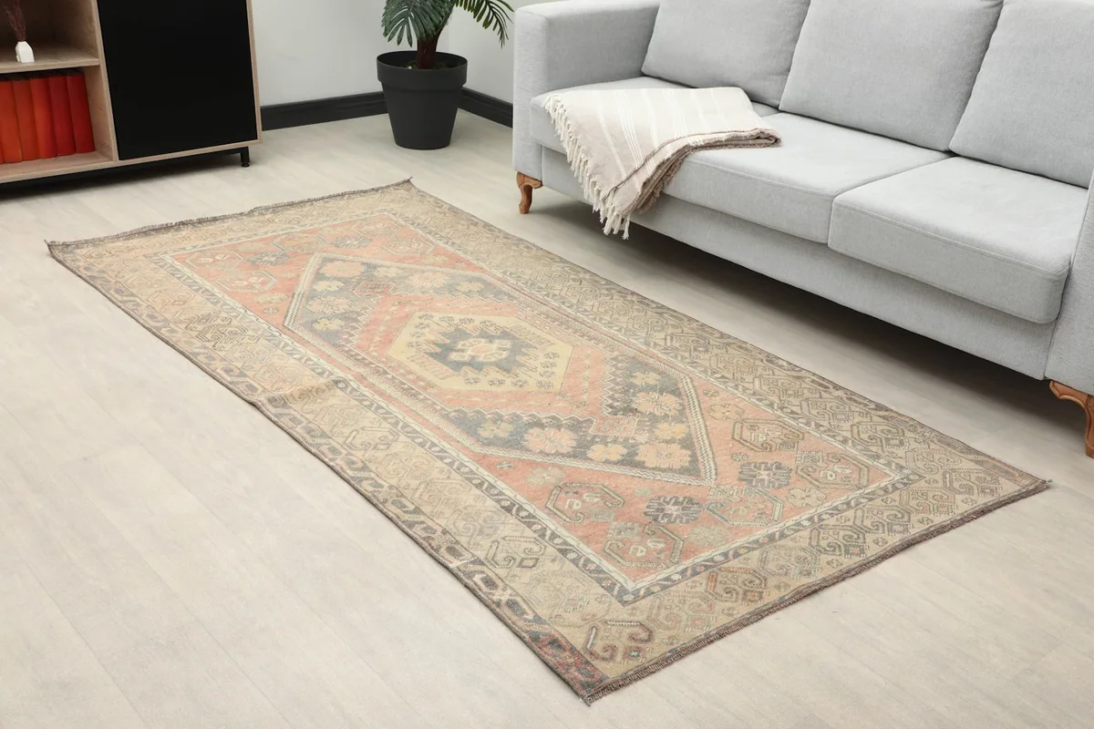 Angled view of the rust and gray vintage rug on a light floor in a home setting