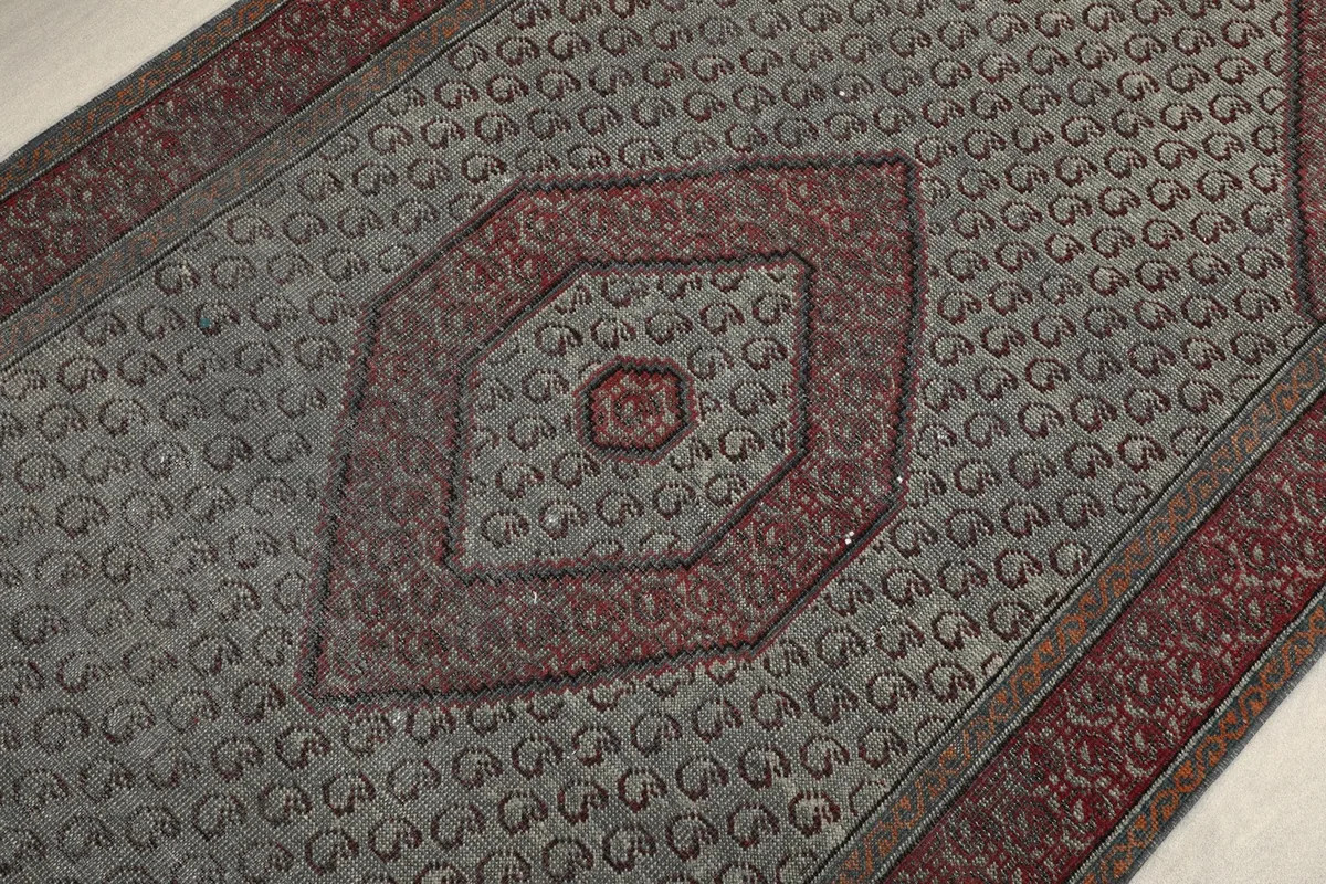 Detailed shot of the central rust medallion and the small repeating geometric elements in the gray field