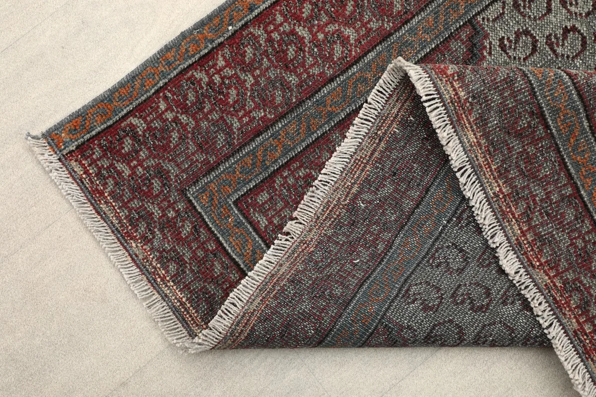 Corner of the rug folded to reveal the thickness of the wool pile and cotton foundation