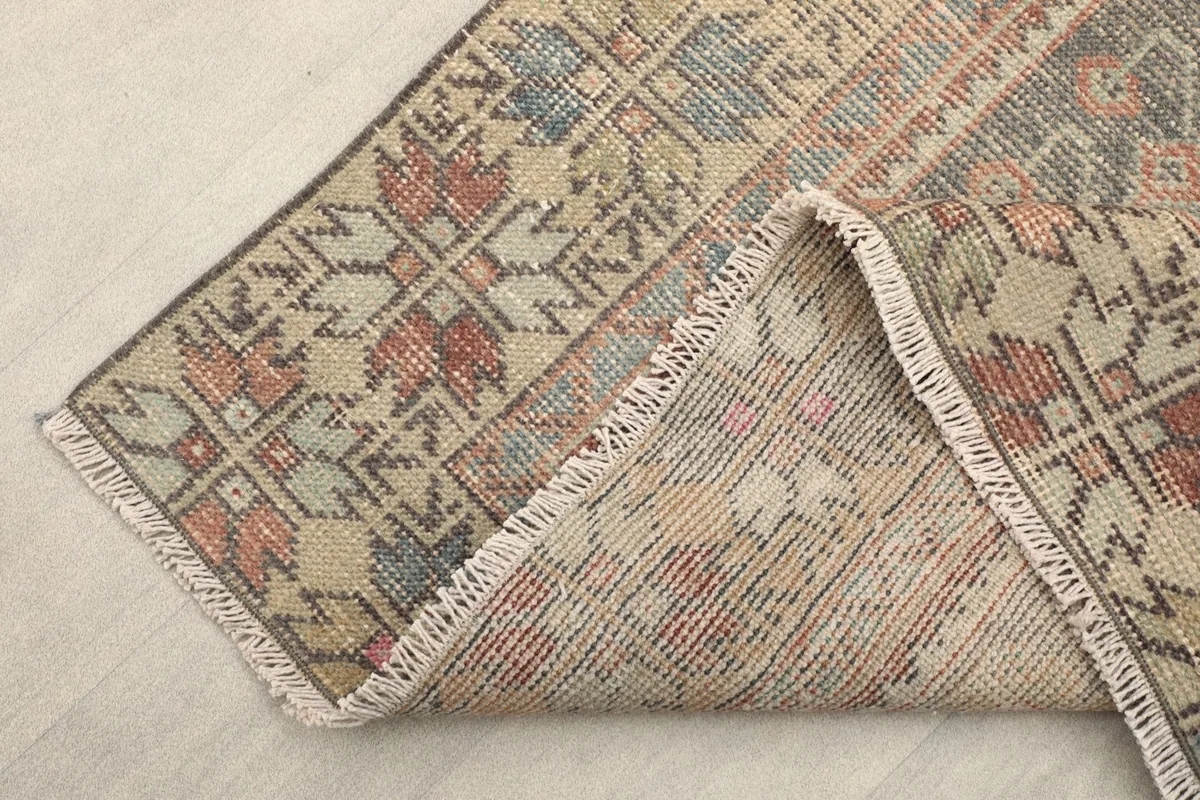 View of the back of the rug and fringe, showing the cotton foundation and hand-knotted construction