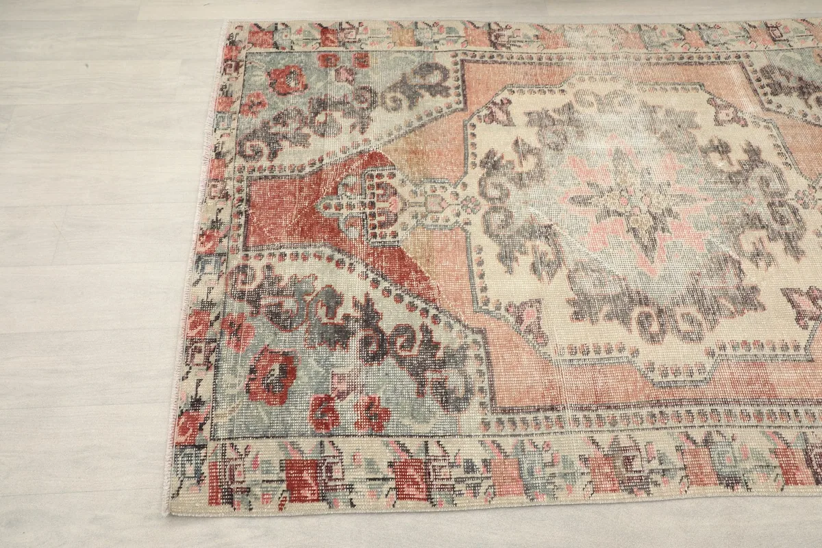 Close-up of the rug's corner, showing the rust and gray motifs in the border design