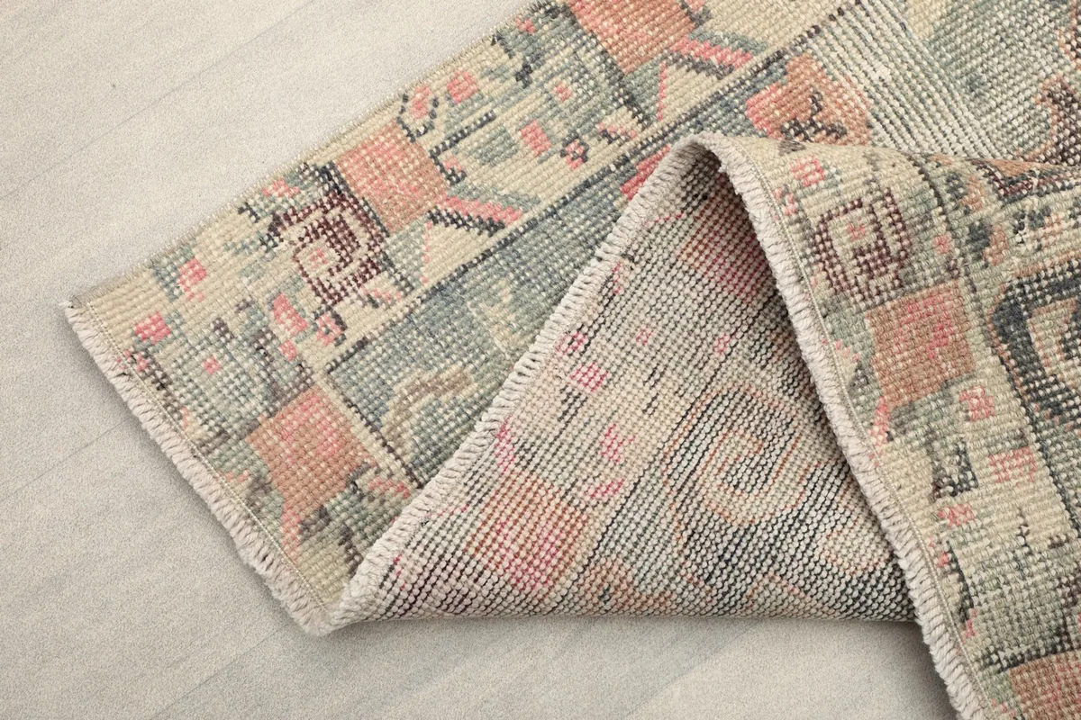 View of the rug folded to show the back of the cotton foundation and the fringe detail