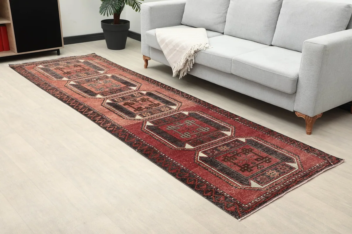 Angled view of the red and black geometric runner extending into a room with a sofa.