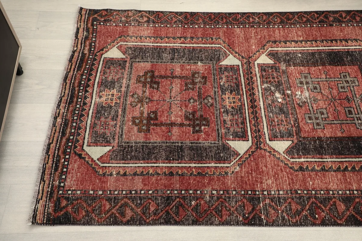 Detailed view showing the wool pile texture and geometric patterns on the red and black runner.