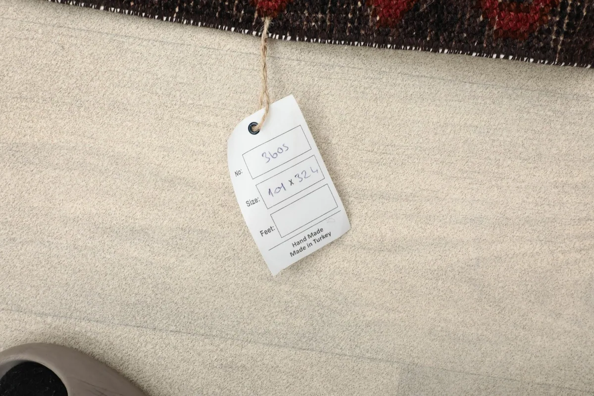 Product tag attached to the rug, indicating it is hand-made in Turkey with size information.