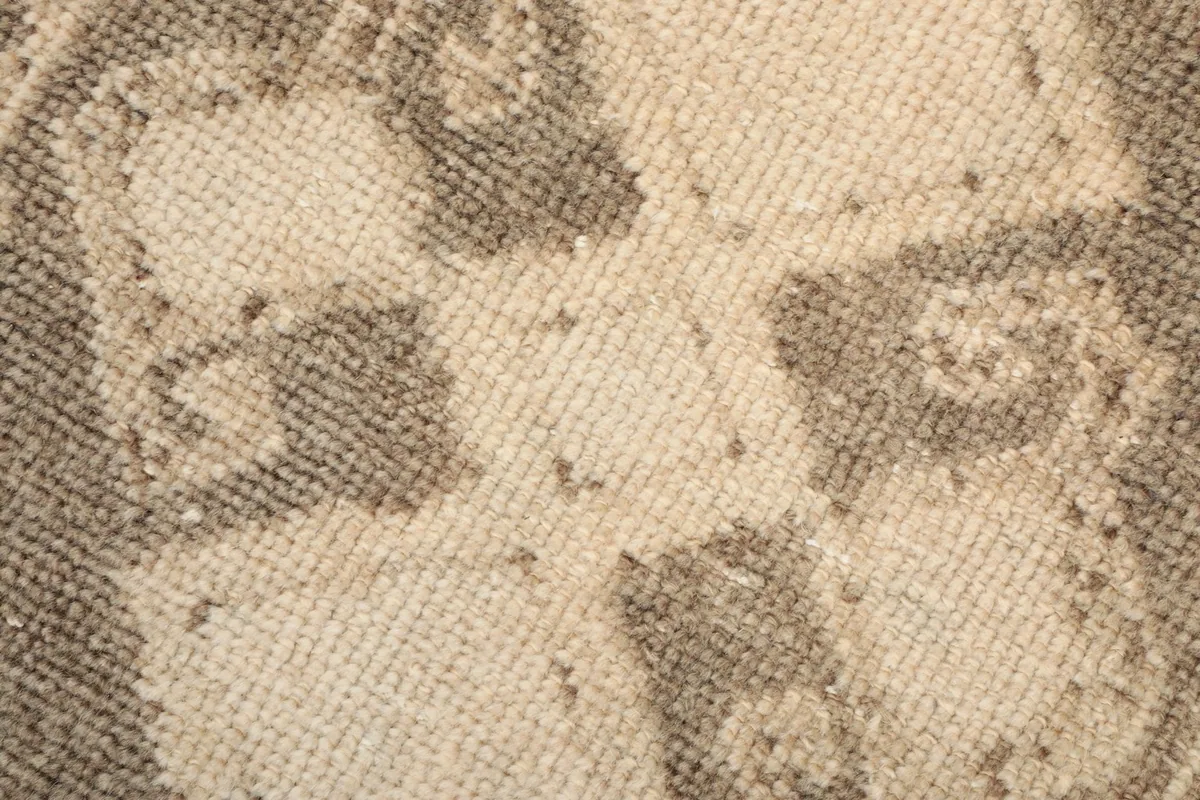 Macro shot of the low wool pile and hand-knotted texture of the rug, showing color variations