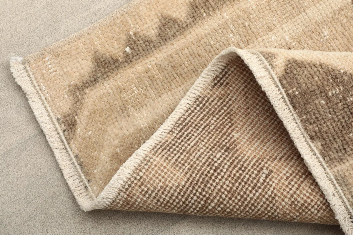 Folded corner of the rug revealing the cotton foundation and reverse side of the knots
