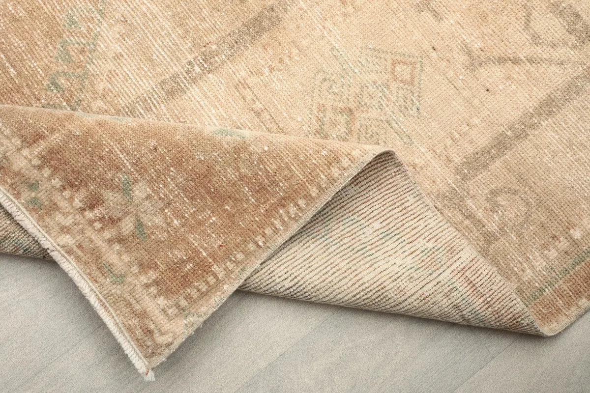 Close-up of the low wool pile and folded corner, revealing the rug's construction and patina.