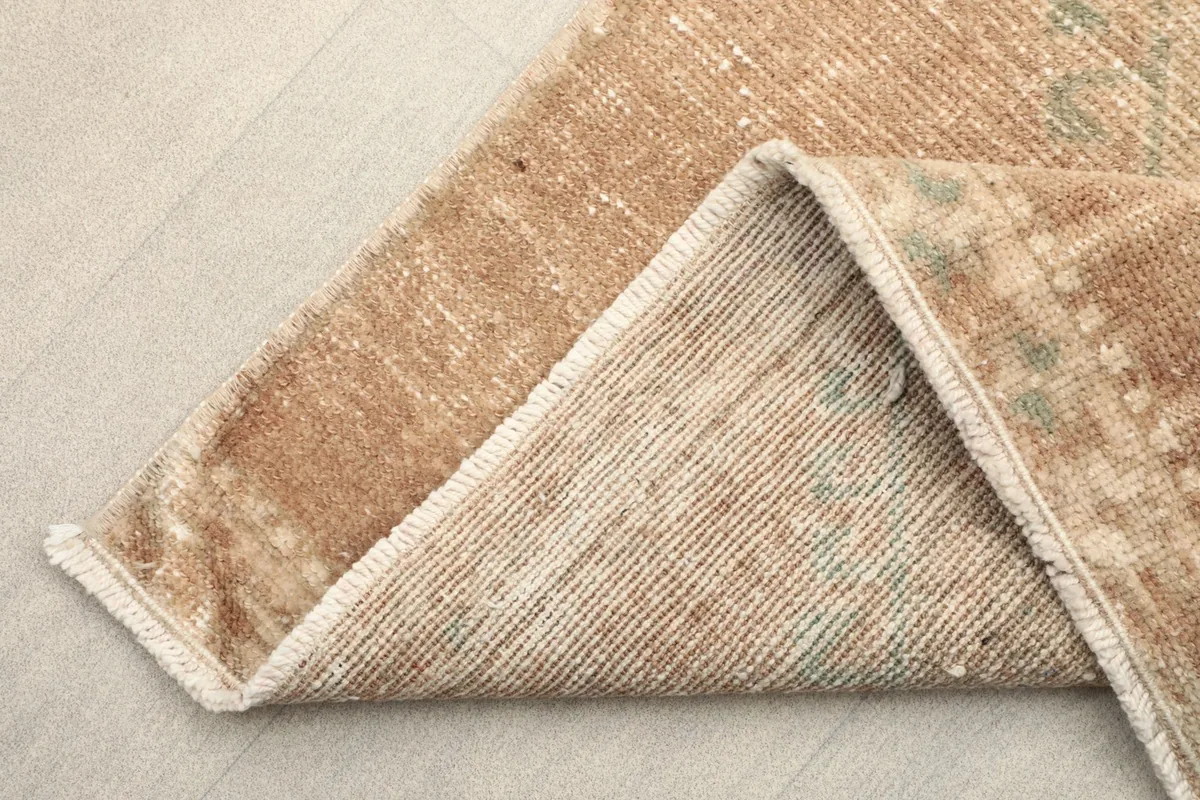 Corner of the rug folded to show the cotton foundation and the reverse side of the hand-knotted construction.