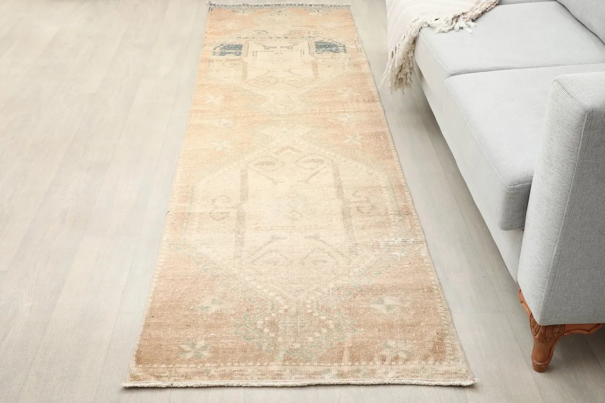Overhead view of the beige runner rug laid on a light floor next to a sofa.