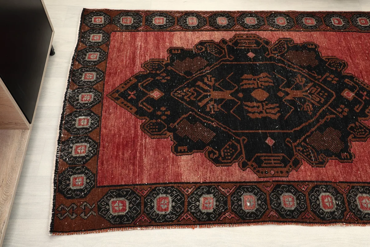 Detailed view of the black geometric medallion and outer border on the red Anatolian runner