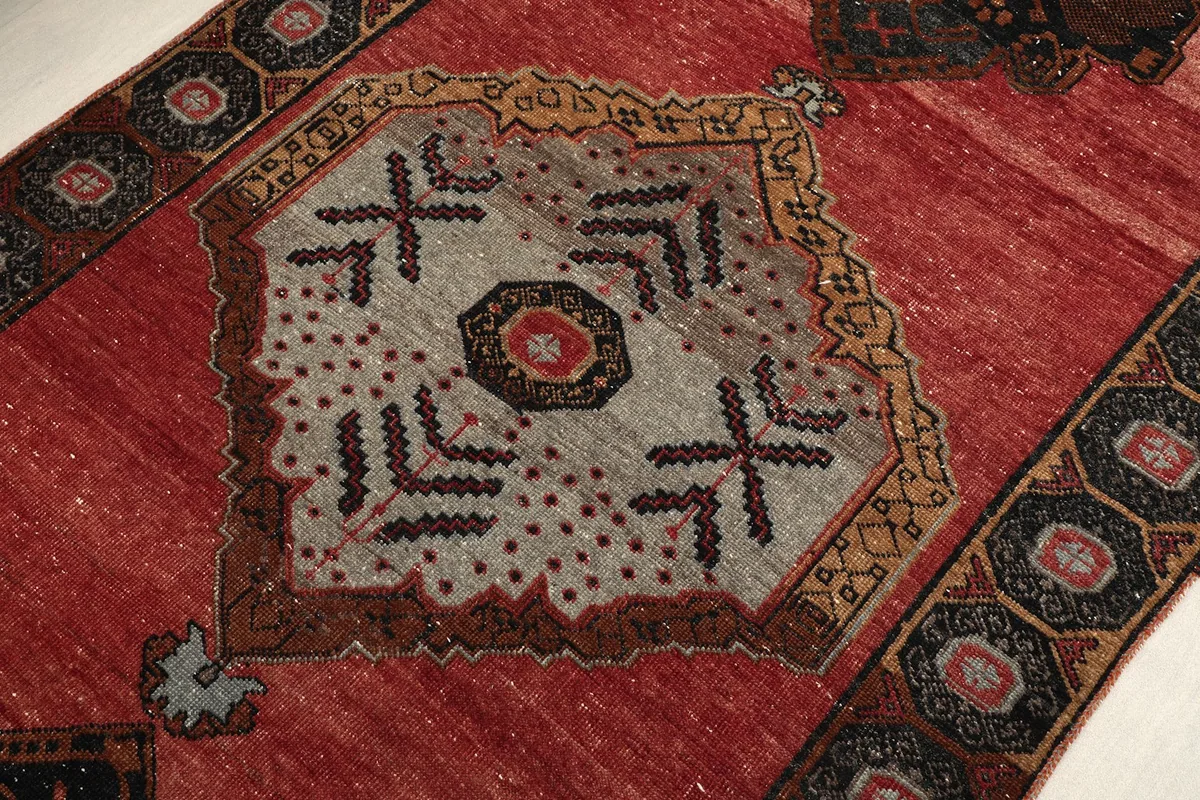 Close-up of a central gray geometric medallion with red and black accents on the runner