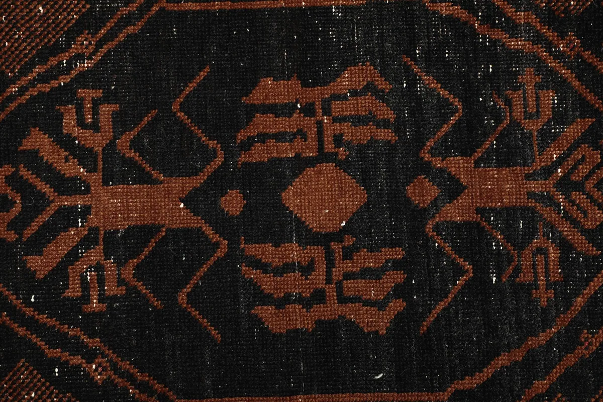 Macro view of the hand-knotted wool pile, showing texture and colors within a black motif