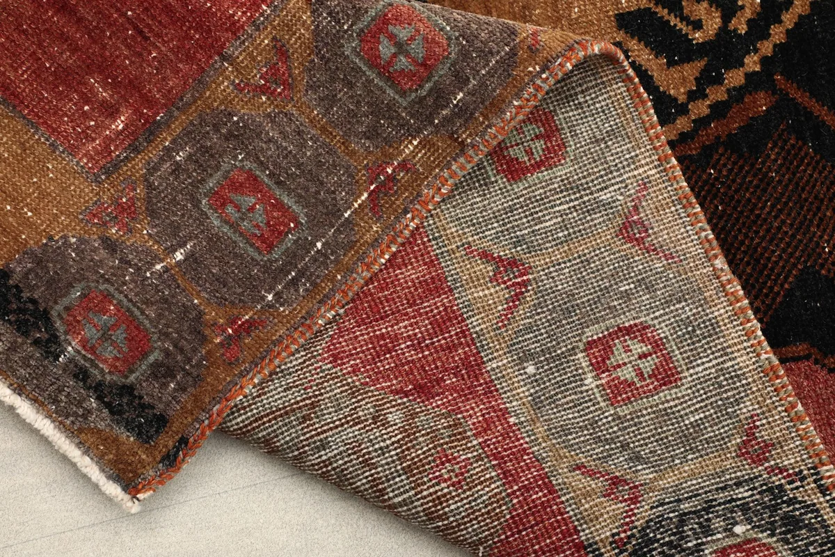 View of the rug's reverse side and folded edge, showing the cotton foundation