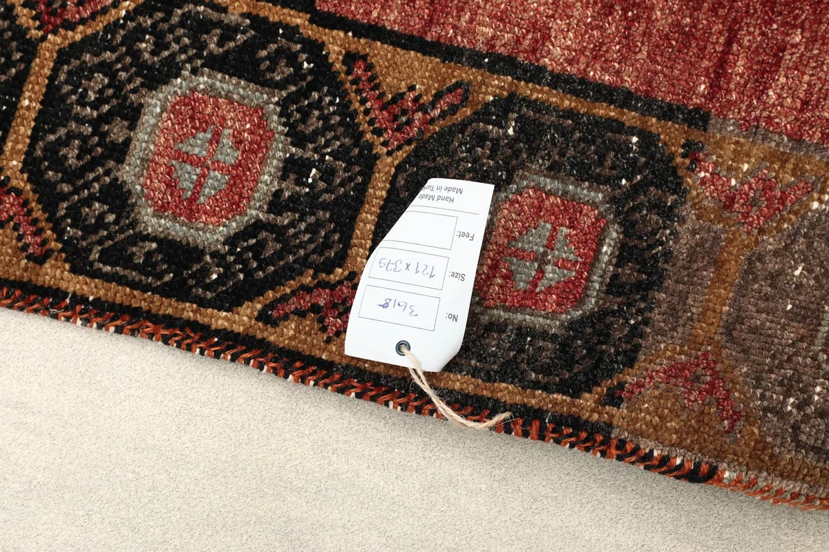 Close-up of the rug's edge with a size tag, detailing the hand-knotted construction