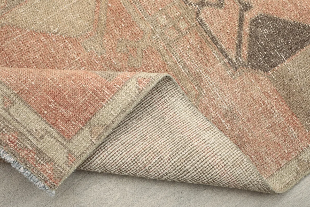 Close-up detail of the rug's lifted corner, revealing the hand-knotted wool pile and cotton foundation.