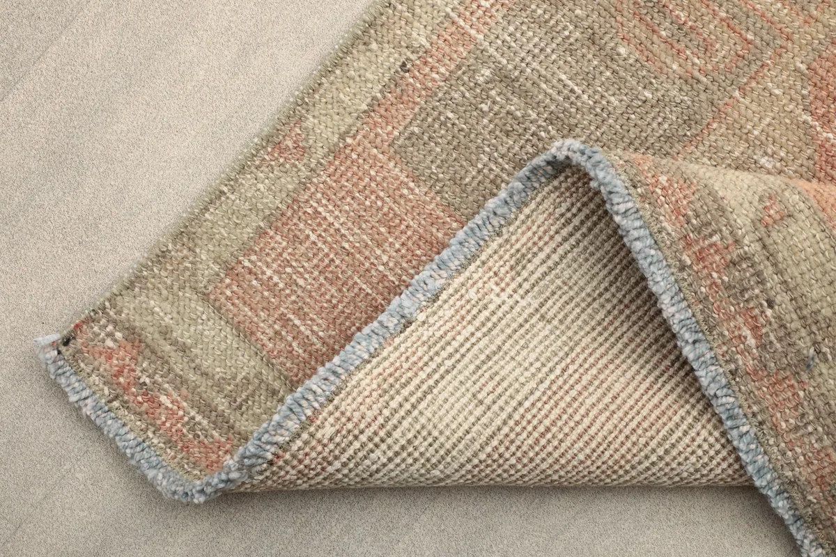 Underside view of the rug's corner, showing the tightly woven cotton foundation and short fringes.