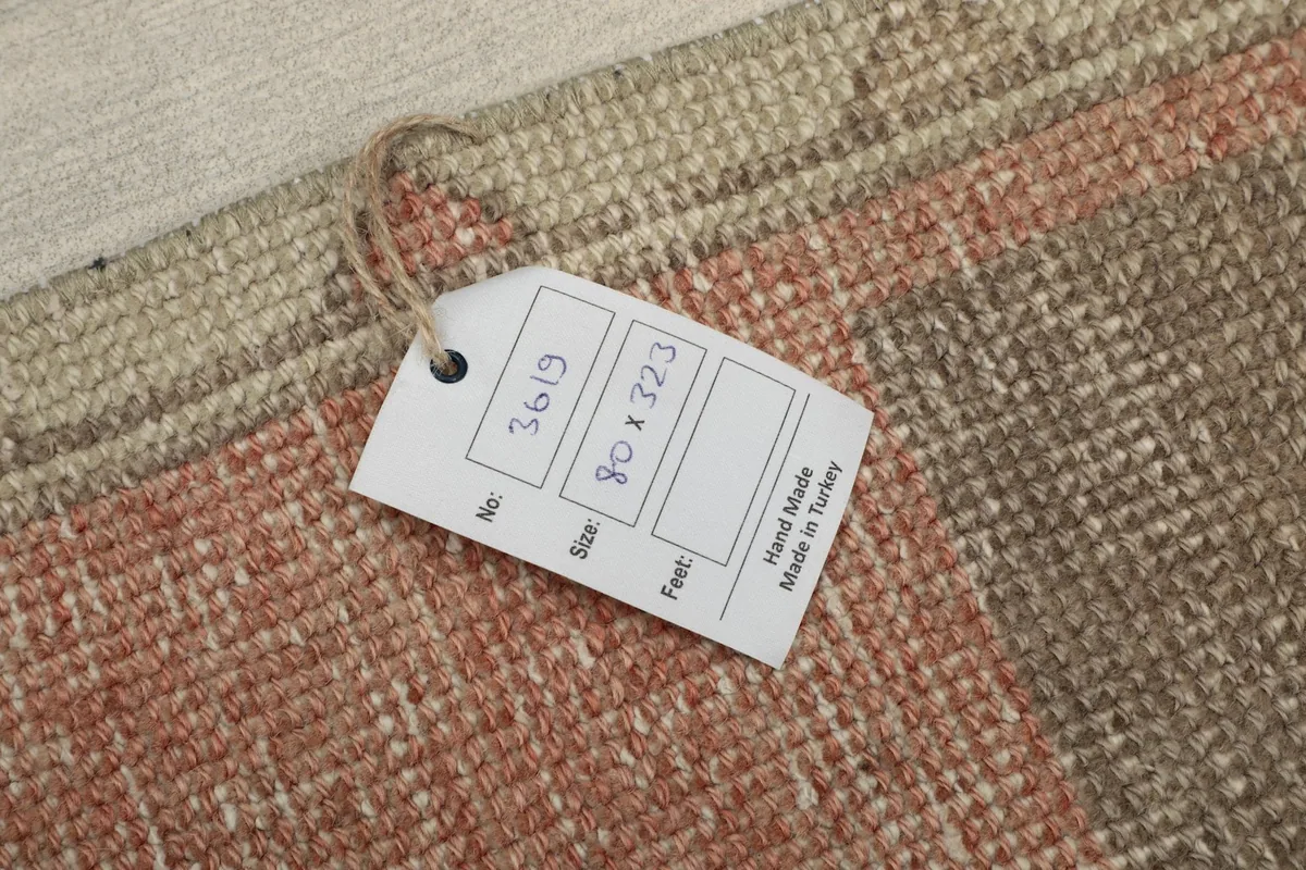 Close-up of the rug with its product tag, displaying 'Hand Made in Turkey' and size information.