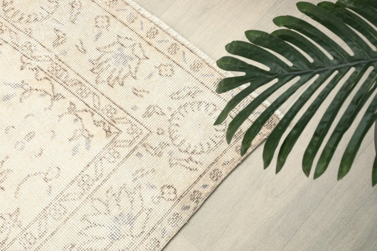 Overhead corner view of the rug with a plant leaf, showing pattern detail
