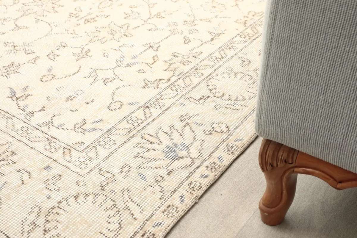 Close-up of the rug's corner next to a sofa leg, showing the border pattern in a room setting