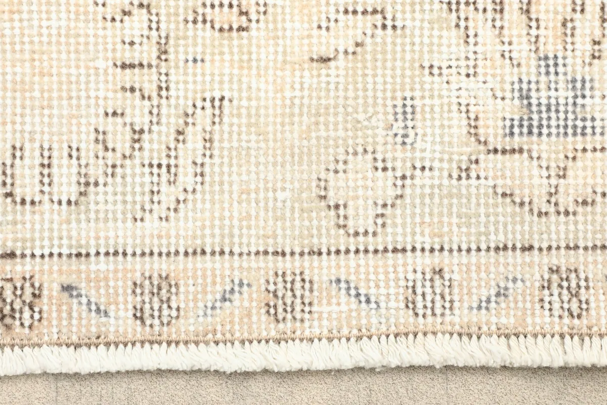 Close-up of the rug's border and fringe, showing low pile and subtle color variations