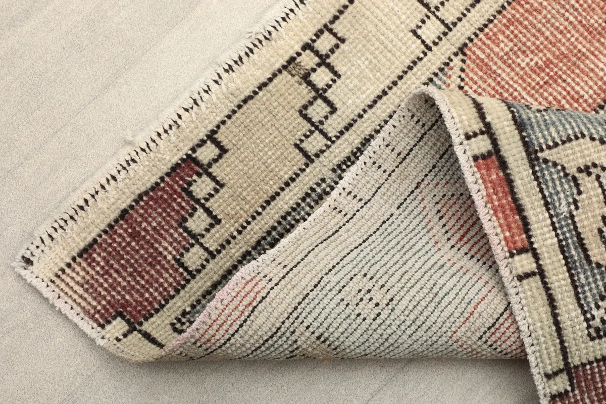 Corner of the runner folded back, revealing the cotton foundation and reverse side.