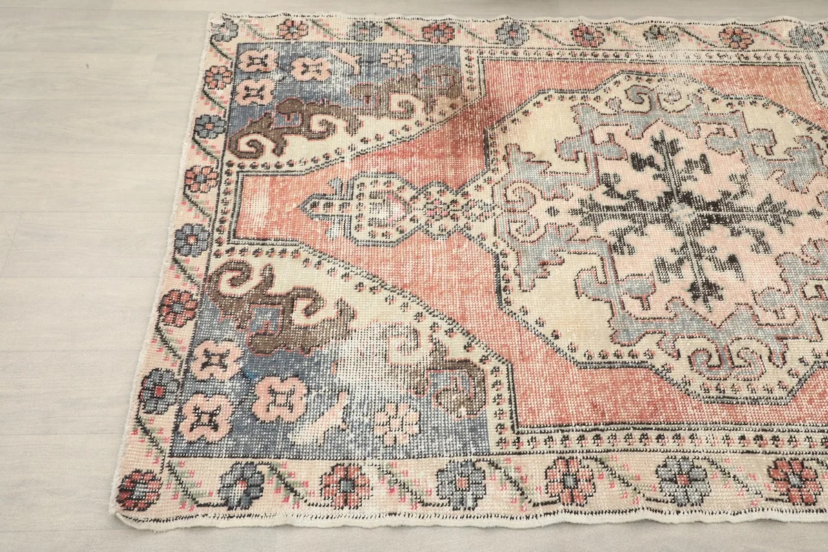 Angled view showing the top left section of the rose and blue vintage rug