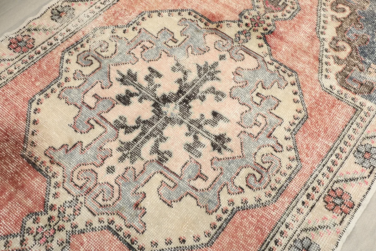 Close-up detail of the central ivory medallion and rose field of the vintage rug