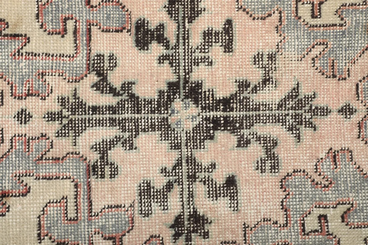 Detailed view of the intricate black and pink geometric pattern within the medallion