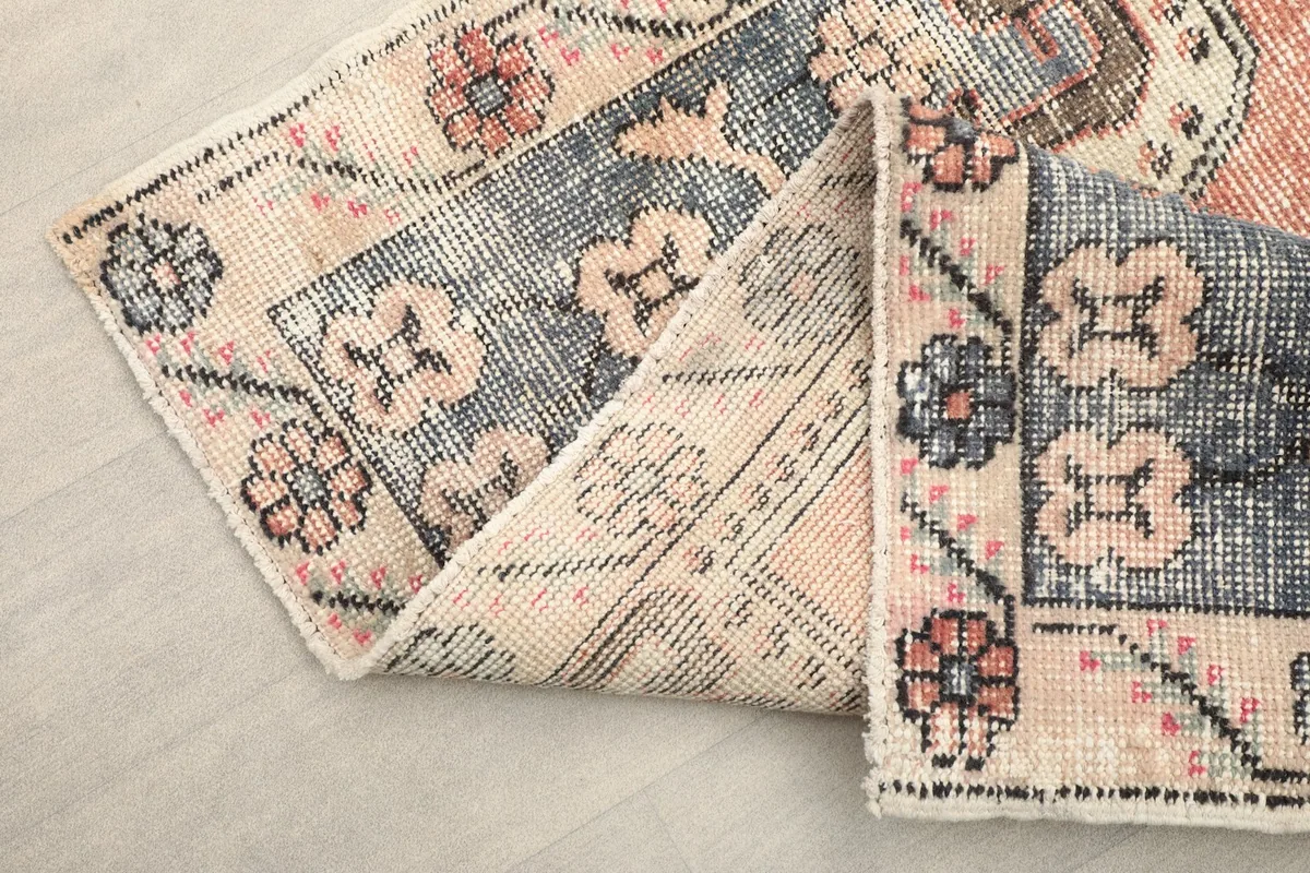 Corner of the vintage rug folded to show the hand-knotted wool pile and cotton foundation