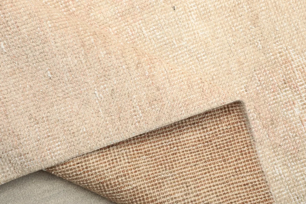 Detail of the low wool pile and the hand-knotted construction, with a glimpse of the foundation.