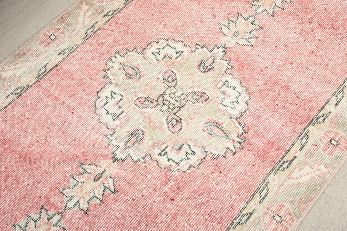 Detailed view of a central ivory medallion motif against the pink background