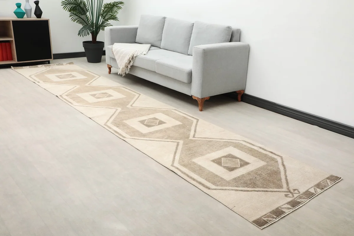 Long runner rug laid out in a modern room with a gray sofa and plant.
