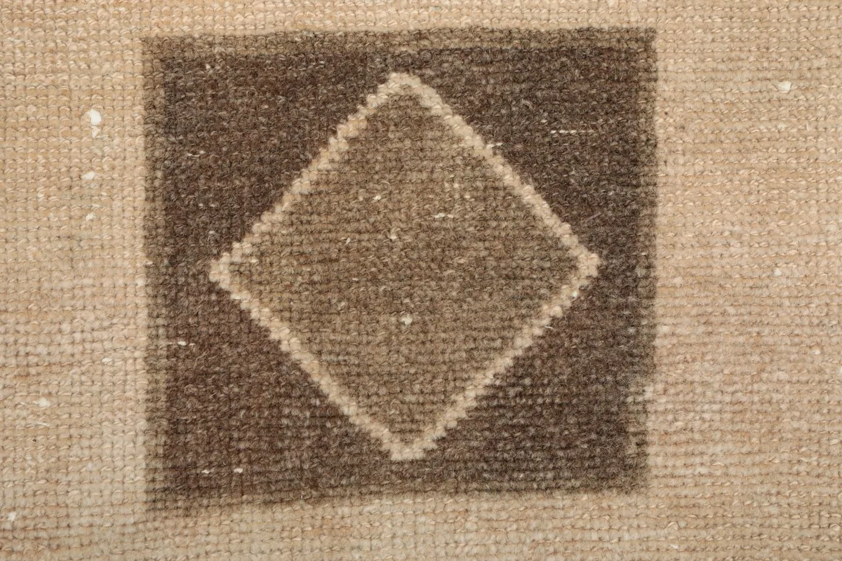 Tight detail of the wool pile and hand-knotted texture within a tan geometric shape.
