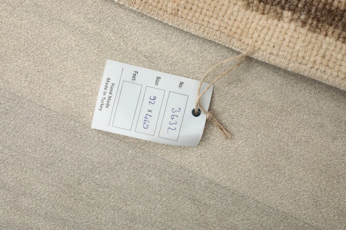 Product tag indicating the rug's size in centimeters and its handmade origin.