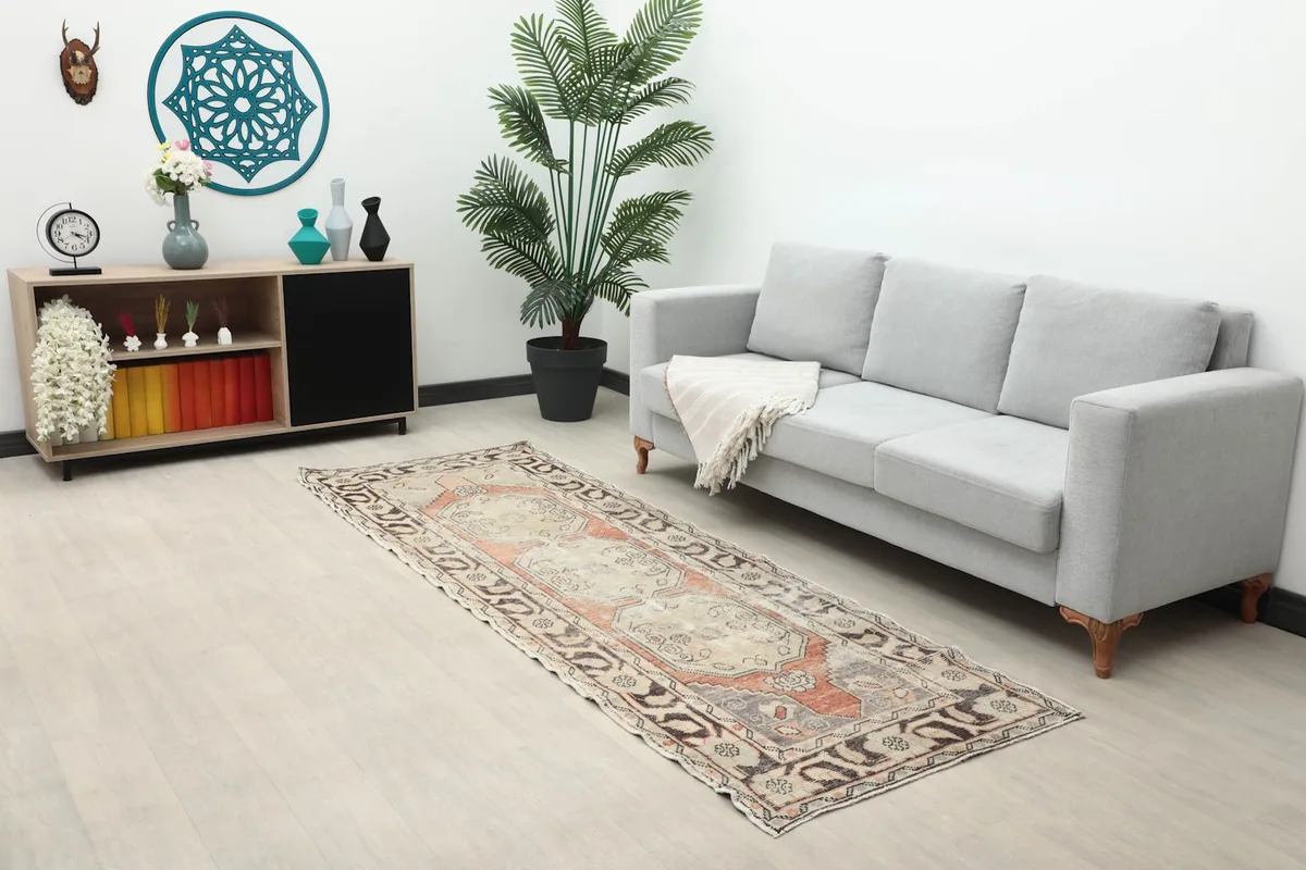 Long view of the beige and rust runner rug in a living space with a gray sofa and decorative elements.