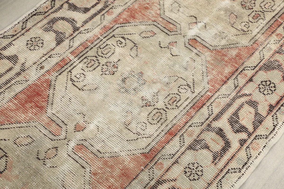 Close-up of the rug's surface, revealing the hand-knotted wool texture and faded vintage appearance.