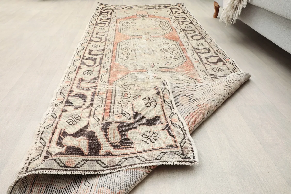 The runner rug partially folded, illustrating its flexibility and the overall condition of the vintage piece.