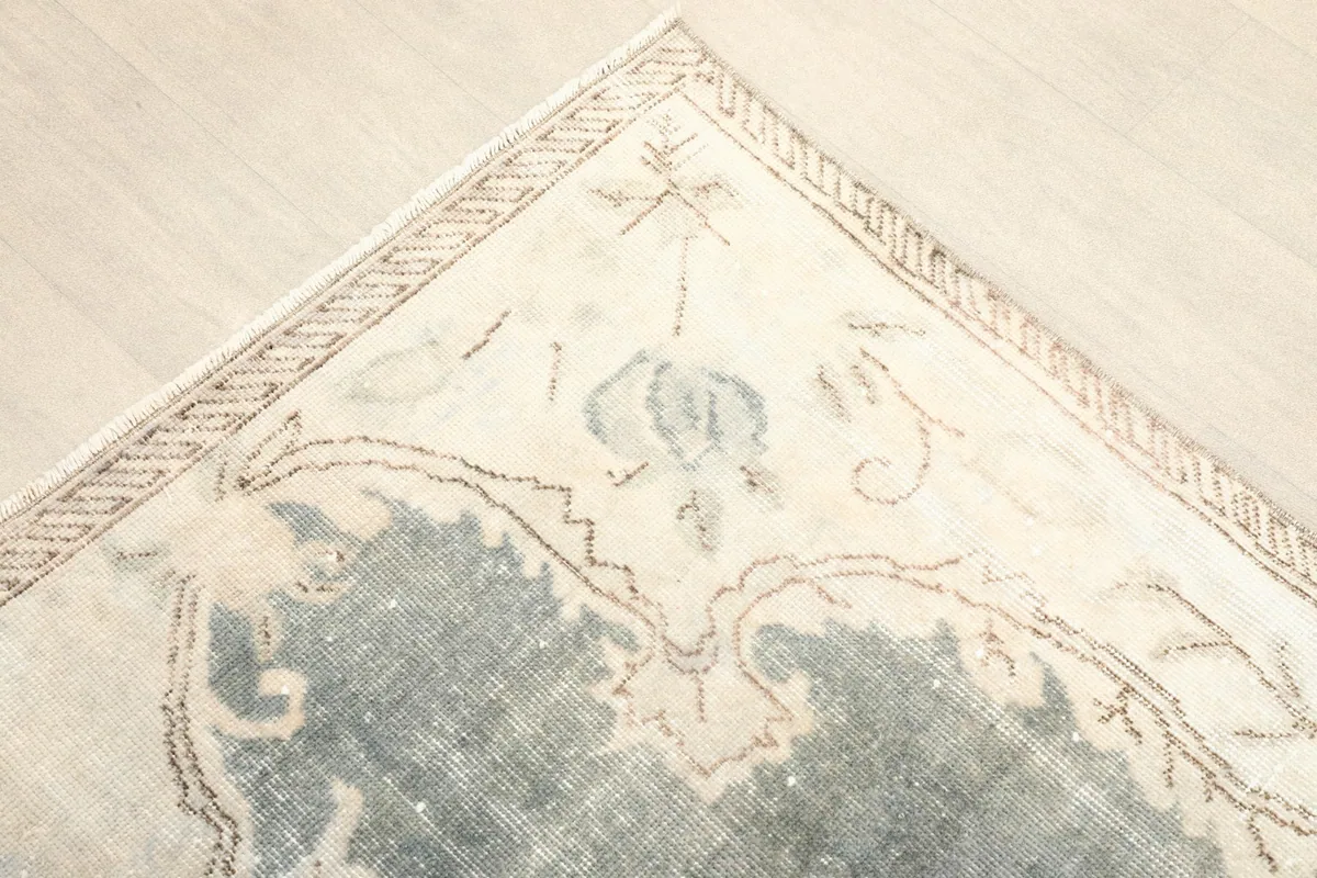 Corner detail showing the muted gray field, ivory floral motifs, and border design