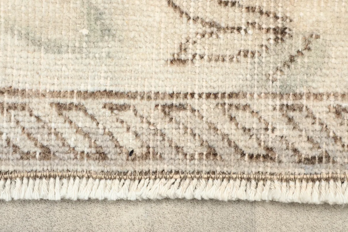 Close-up of the rug's border with a geometric pattern and short, even fringe