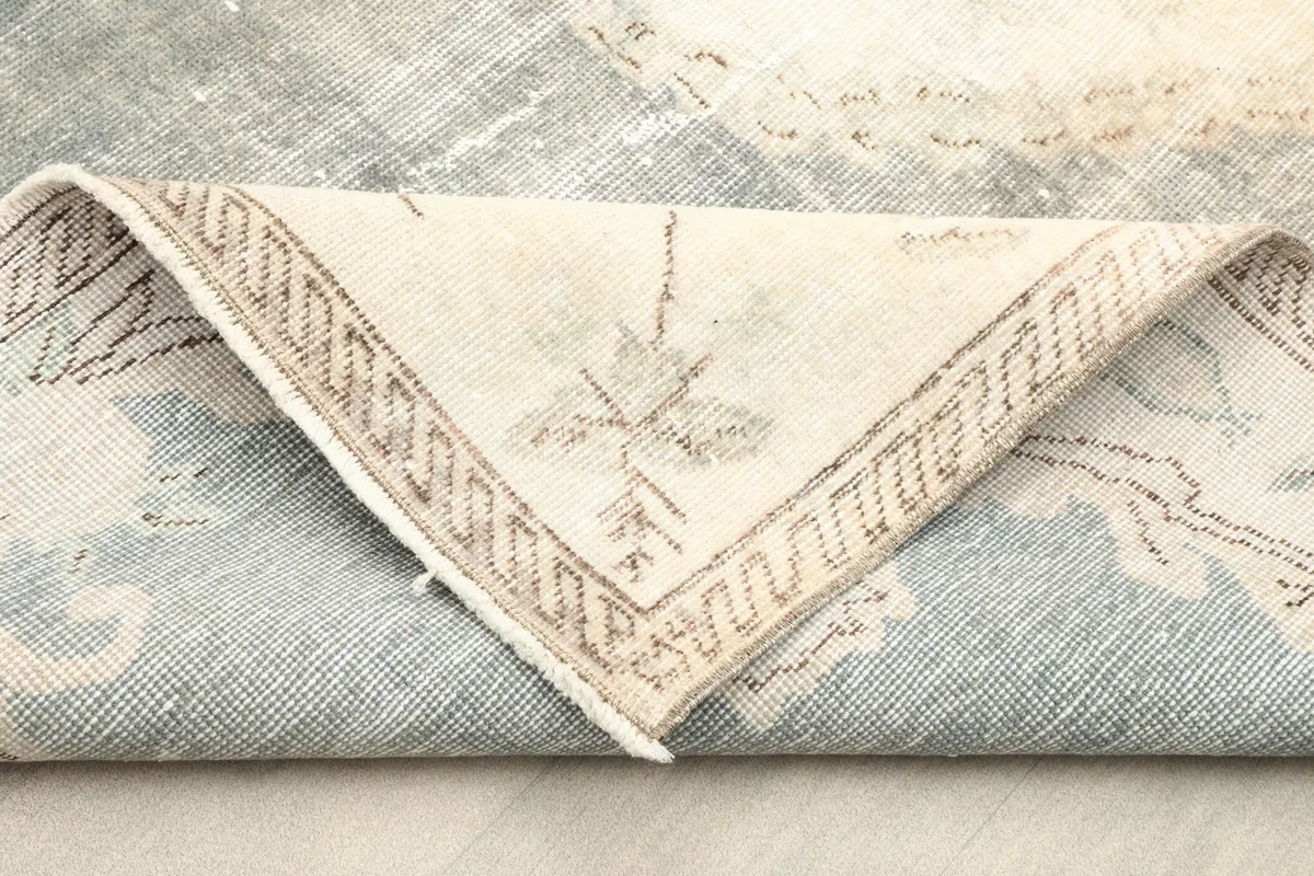 Folded corner of the rug displaying the reverse side, cotton foundation, and border detail