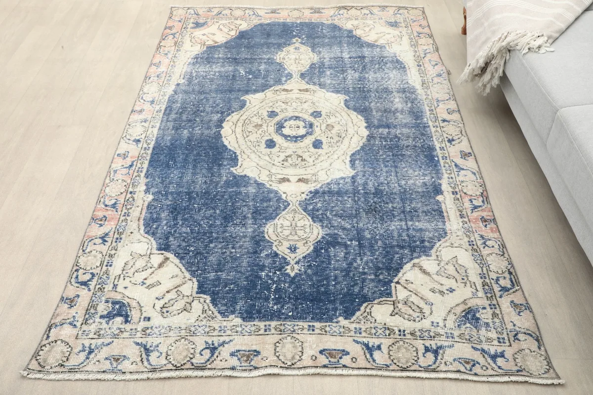 Vintage navy blue area rug with beige medallion in a room setting, showing its scale.