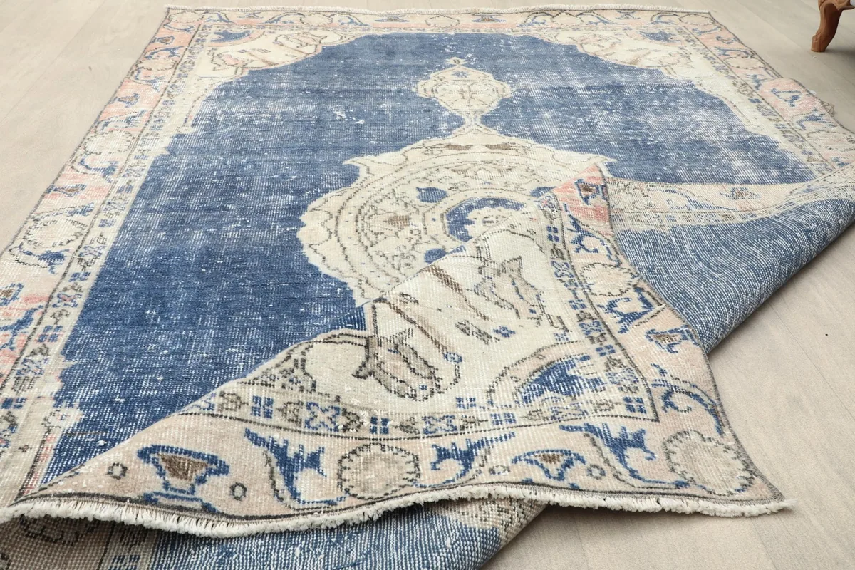 Detail of the low wool pile texture and the distressed surface of the vintage rug.