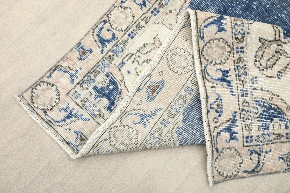 View of the rug folded to show the thickness and the back of the hand-knotted wool pile.