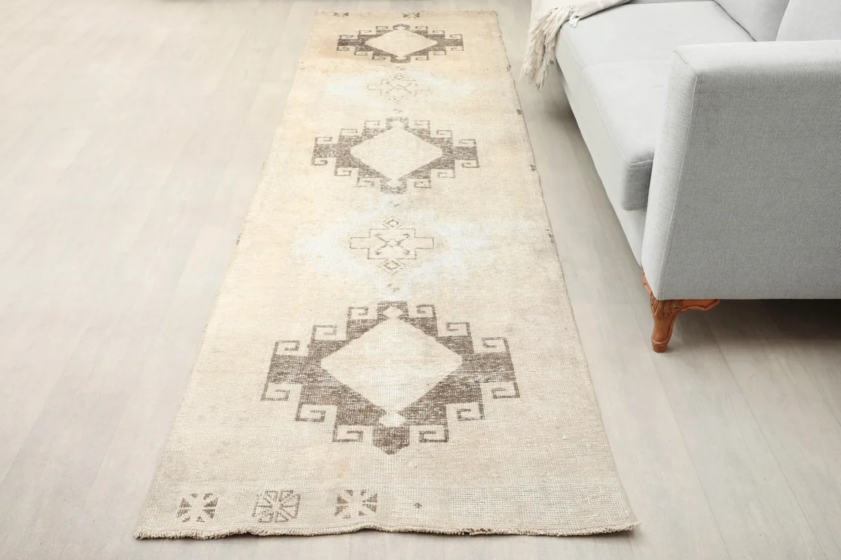 Vintage runner rug laid out in a room, showing its length and pattern alongside a sofa.