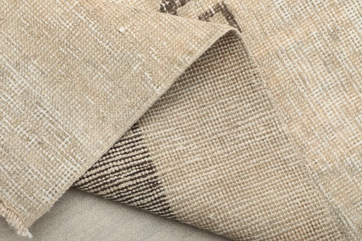 Folded corner of the rug, showing the reverse side and the tightly woven cotton foundation.