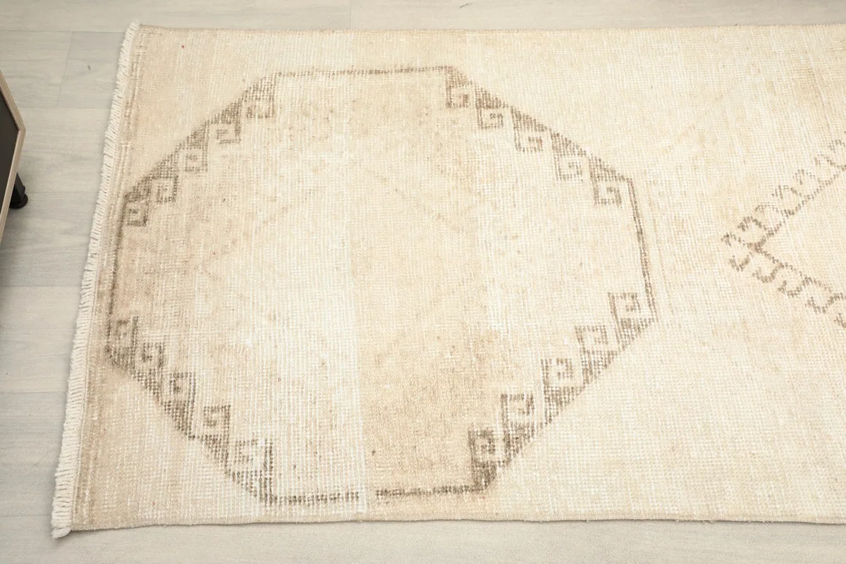 Detailed view of another brown geometric motif and the subtle texture of the beige pile