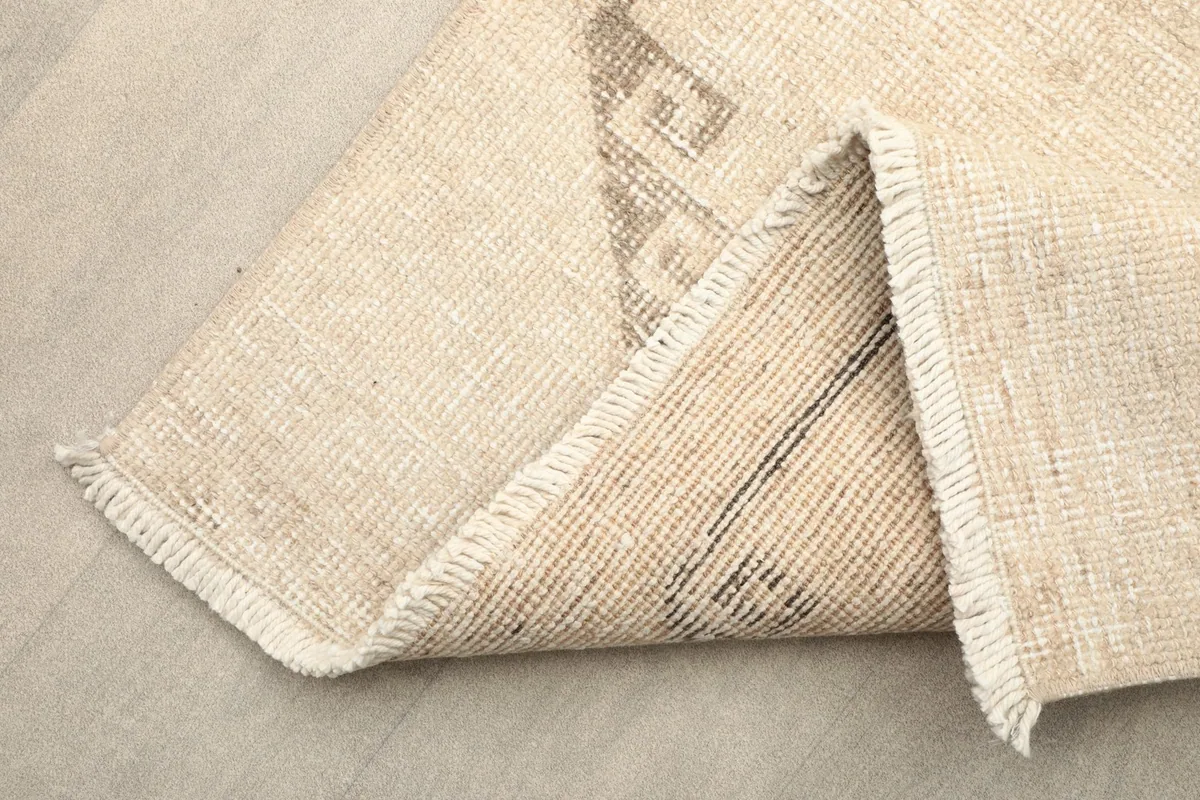 Folded corner of the rug showing the hand-knotted wool pile and cotton foundation