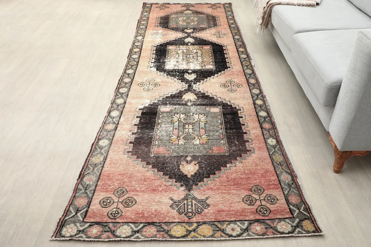 Rose and black vintage runner rug in a long hallway with a light gray couch